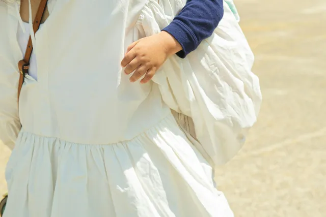 A parent carrying a young child, taking the child's weight through their hands and wrists