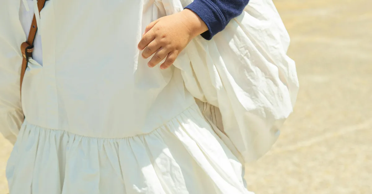 A parent carrying a young child, taking the child's weight through their hands and wrists